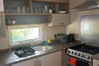 a kitchen with a sink and a stove and a window at Seaside Lodge Haven in St Osyth in Jaywick Sands