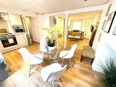 a living room with a glass table and white chairs at Historical Building - Cozy Basement Apartment- Central Location in Cambridge