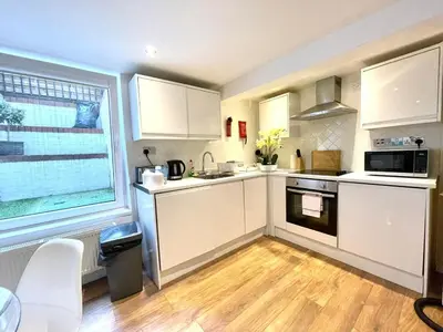 a kitchen with white cabinets and a wooden floor at Historical Building - Cozy Basement Apartment- Central Location in Cambridge