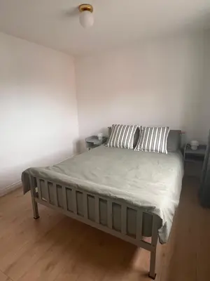 a bed in a white room with two night stands at La CAZA Guest House in Royston