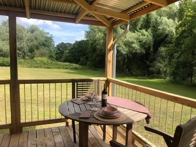 a table on a porch with a view of a field at Okovango Cabin in Holton