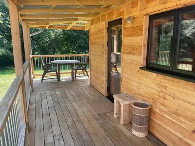 a porch of a wooden cabin with a table and chairs at Okovango Cabin in Holton