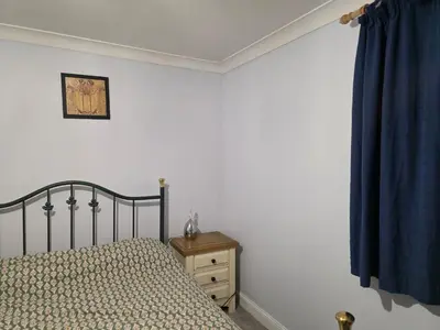 a bedroom with a bed and a blue curtain at Stay Near Colchester twn centre2 in Colchester