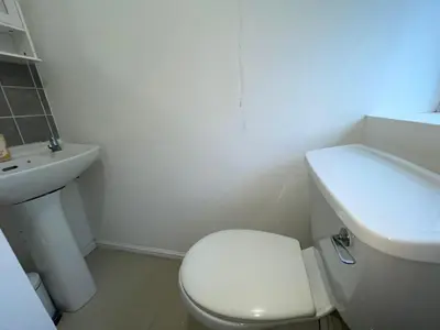 a white bathroom with a toilet and a sink at Cosy Studio in Stevenage