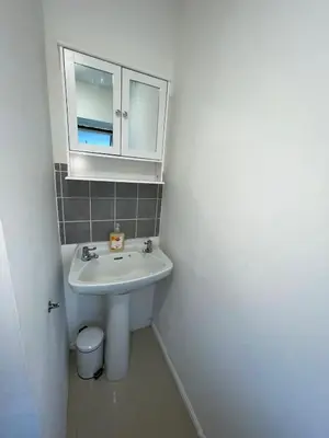 a white bathroom with a sink and a mirror at Cosy Studio in Stevenage