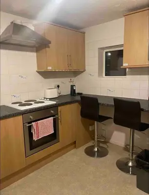 a kitchen with a stove and two chairs in it at Cosy Studio in Stevenage