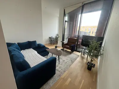 a living room with a blue couch and a tv at Jewel of Chelmsford in Chelmsford