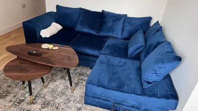 a blue couch sitting next to a wooden table at Jewel of Chelmsford in Chelmsford