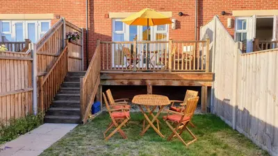 a patio with a table and chairs and an umbrella at Martello Sunrise - Luxury 3-bedroom Seaview Beach House in Felixstowe