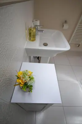 a bathroom with a sink and a vase of flowers at Martello Sunrise - Luxury 3-bedroom Seaview Beach House in Felixstowe