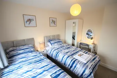 a bedroom with a bed with a blue and white comforter at Martello Sunrise - Luxury 3-bedroom Seaview Beach House in Felixstowe