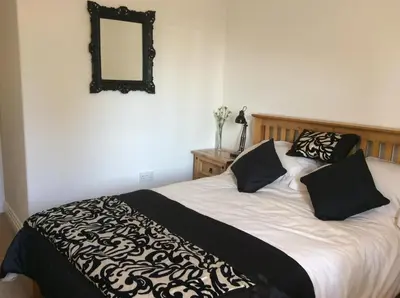 a bed with black and white sheets and a mirror at Beightons Bed and Breakfast in Bury Saint Edmunds