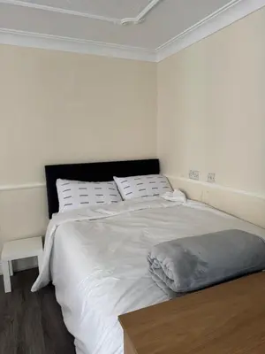 a bedroom with a large bed with white sheets and pillows at Fully en-suite with kitchen