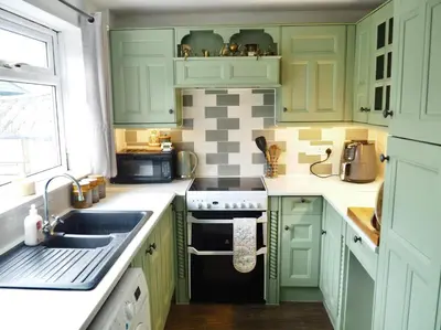 a kitchen with green cabinets and a sink at Cosy Room in Debenham in Debenham