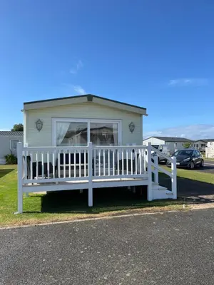 a white house with a porch and a fence at 2 Bedroom Mini Lodge near the beach in Walton-on-the-Naze