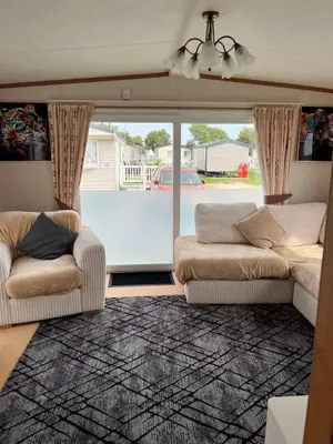a living room with two couches and a large window at 2 Bedroom Mini Lodge near the beach in Walton-on-the-Naze