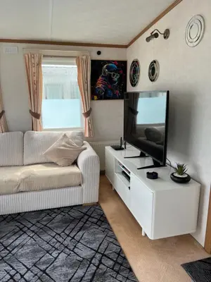 a living room with a white couch and a flat screen tv at 2 Bedroom Mini Lodge near the beach in Walton-on-the-Naze