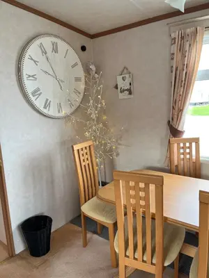 a dining room with a large clock on the wall at 2 Bedroom Mini Lodge near the beach in Walton-on-the-Naze