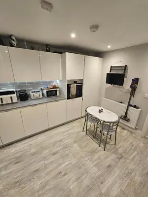 a kitchen with white cabinets and a table in a room at Bright spacious room in Manningtree in Manningtree