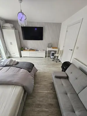 a bedroom with a couch and a tv on the wall at Bright spacious room in Manningtree in Manningtree