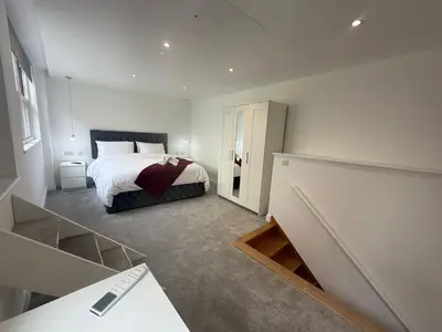 a bedroom with a large bed and a staircase at Stylish 3 bed spacious flat in Brentwood