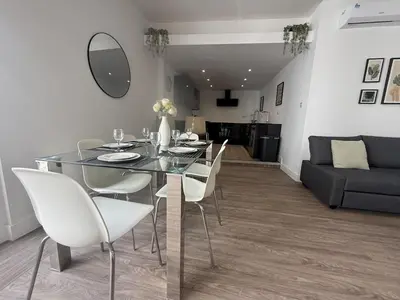 a dining room with a glass table and white chairs at Stylish 3 bed spacious flat in Brentwood