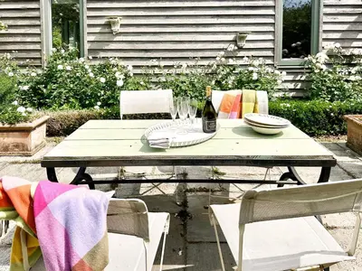 a picnic table with two chairs and a bottle of wine at The Barn at Orford Lodge by The Suffolk Cottage Collection in Orford