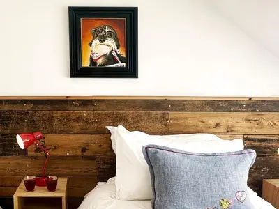 a painting of a dog on a wall above a bed at The Barn at Orford Lodge by The Suffolk Cottage Collection in Orford