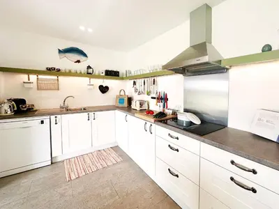 a kitchen with white cabinets and stainless steel appliances at The Barn at Orford Lodge by The Suffolk Cottage Collection in Orford
