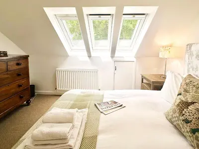 a bedroom with a large white bed with a skylight at The Barn at Orford Lodge by The Suffolk Cottage Collection in Orford