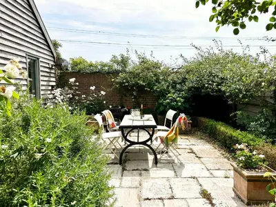a patio with a table and chairs in a garden at The Barn at Orford Lodge by The Suffolk Cottage Collection in Orford