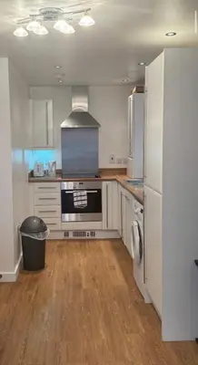 a large kitchen with white cabinets and a refrigerator at Hamilton Court in Great Burstead