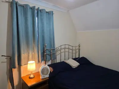 a bedroom with a bed and a blue curtain at Stay Near Colchester twn centre5 in Colchester