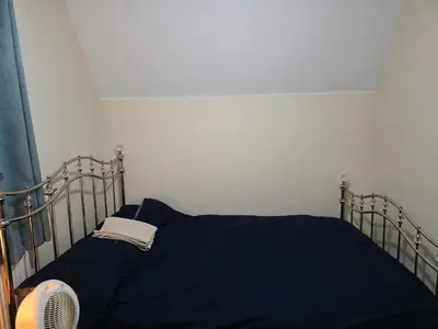a bed with a blue blanket and a fan at Stay Near Colchester twn centre5 in Colchester