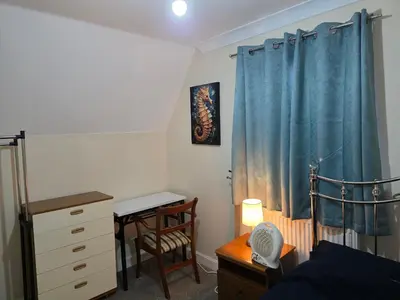 a bedroom with a blue curtain and a desk and a bed at Stay Near Colchester twn centre5 in Colchester