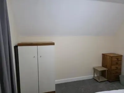 a bedroom with a white wall and a dresser at Stay Near Colchester twn centre4 in Colchester
