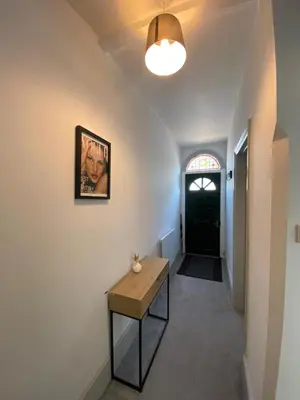 a hallway with a table and a picture on the wall at Three Bedroom Home Close to central Cambridge in Chesterton