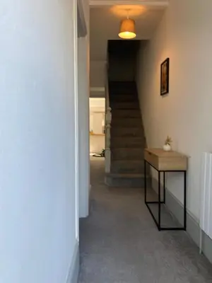 a hallway with a staircase with a table and a stair case at Three Bedroom Home Close to central Cambridge in Chesterton