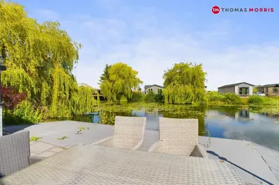 a table and chairs in front of a river at Lakeside Lodge Retreat with Views in Fenstanton