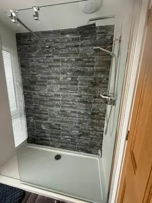 a shower in a bathroom with a brick wall at Lakeside Lodge Retreat with Views in Fenstanton