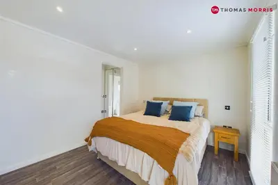 a white bedroom with a bed with blue pillows at Lakeside Lodge Retreat with Views in Fenstanton