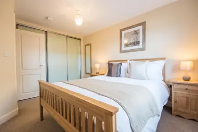 a bedroom with a large bed with white sheets and pillows at Camstay Abbey Street in Cambridge