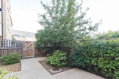 a garden with a tree and a wooden fence at Camstay Abbey Street in Cambridge