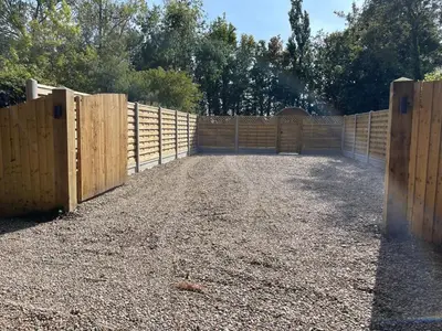 a wooden fence with a gate in a yard at Highgate Cabin in Takeley