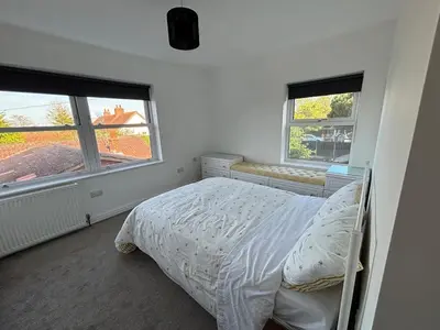 a white bedroom with a bed and two windows at Fernleigh - Lovely Self Catering Apartment in Tollesbury in Tollesbury