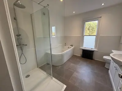 a bathroom with a shower and a tub and a sink at Fernleigh - Lovely Self Catering Apartment in Tollesbury in Tollesbury