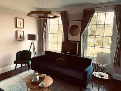 a living room with a black couch and two windows at Stunning Central Georgian Home in Cambridge