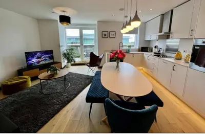 a living room with a table and a kitchen at Penthouse Mill park train station in Cambridge