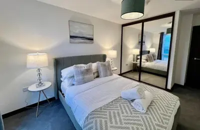 a bedroom with a large bed and a mirror at Penthouse Mill park train station in Cambridge
