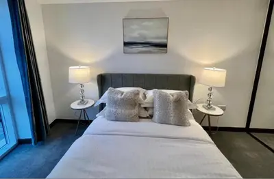 a bedroom with a bed with two tables and two lamps at Penthouse Mill park train station in Cambridge
